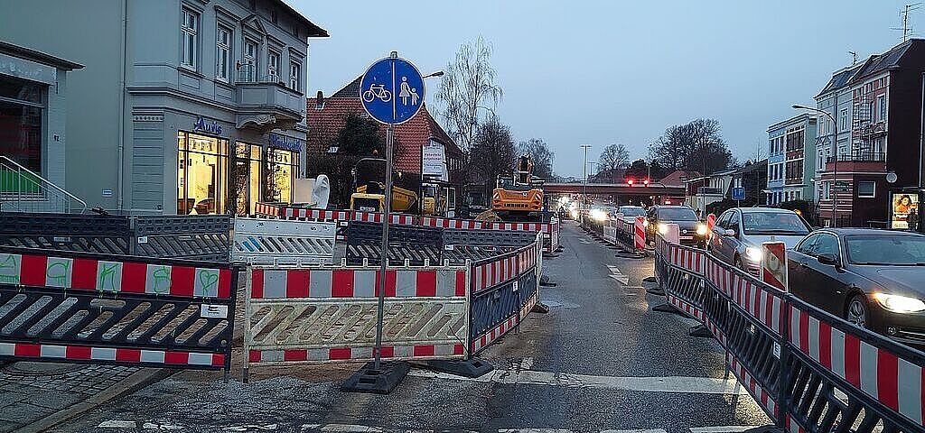 Das Foto zeigt eine Baustelle auf einem Fuß-Radweg. Die Radfahrer und Fußgänger werden auf der Fahrbahn geführt. Das Verkehrsschild erlkaubt das Fahren in Gegenrichtung, obwohl das hier eigentlich nicht erlaubt ist.