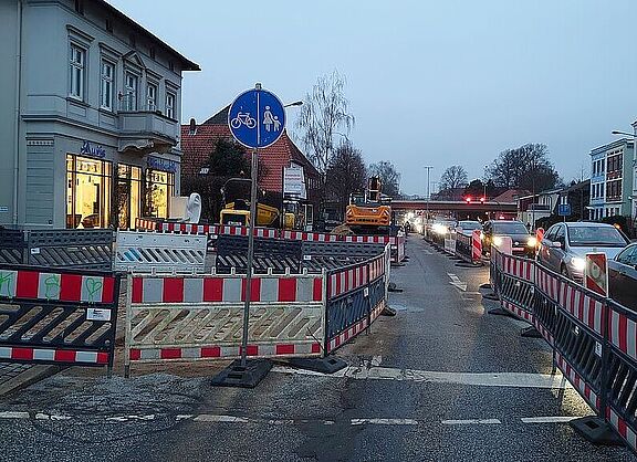 Das Foto zeigt eine Baustelle auf einem Fuß-Radweg. Die Radfahrer und Fußgänger werden auf der Fahrbahn geführt. Das Verkehrsschild erlkaubt das Fahren in Gegenrichtung, obwohl das hier eigentlich nicht erlaubt ist.