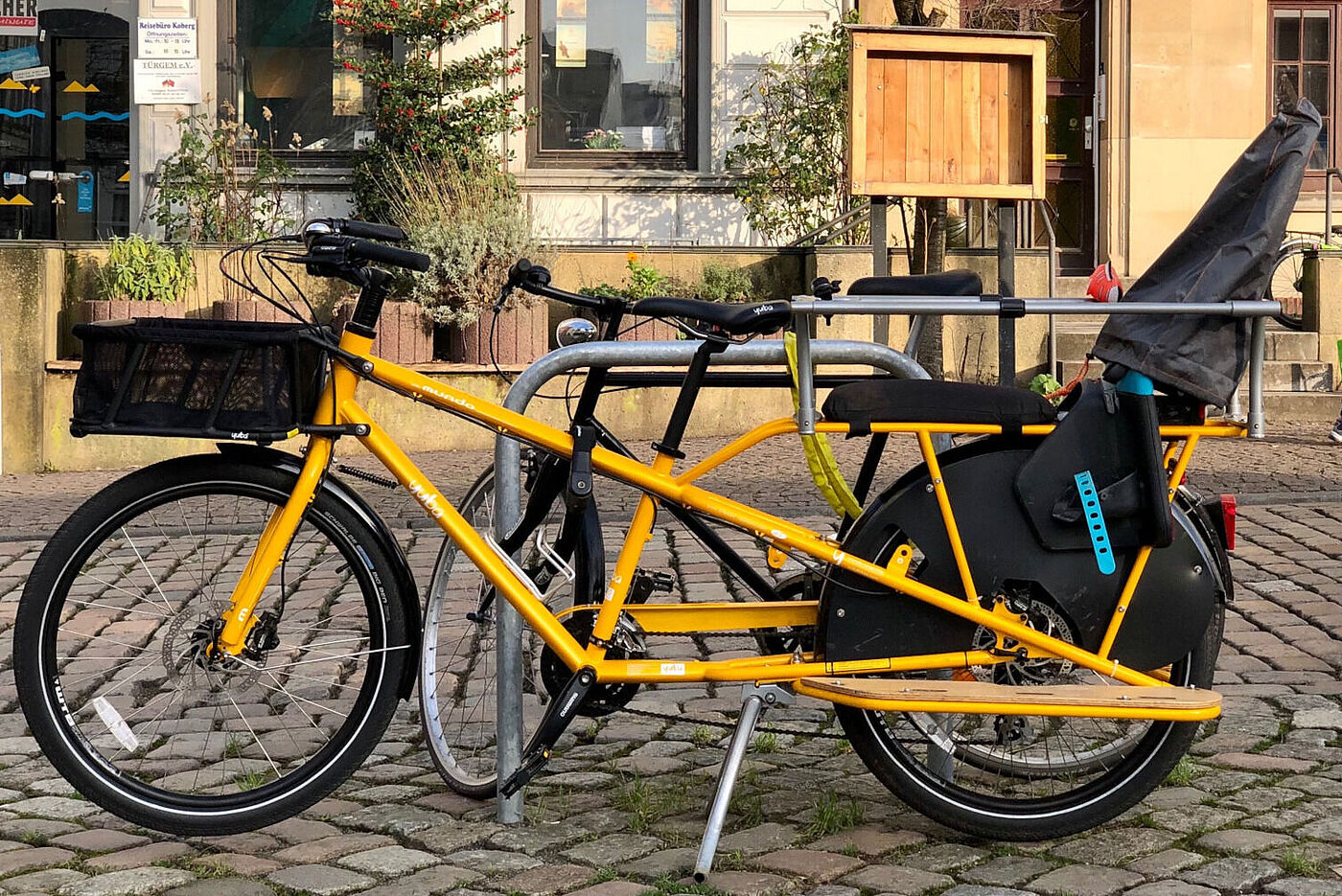 Gelber Kindertransporter mit Sitzbank hinter der Fahrer*in