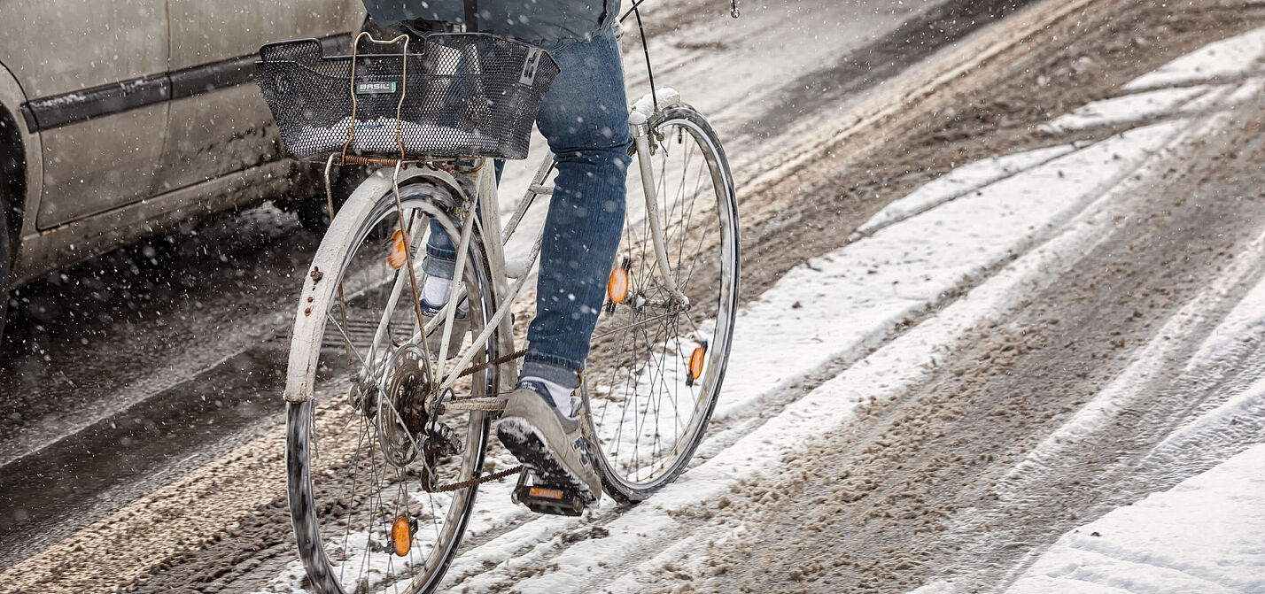 Radfahren im Winter Radfahrer*in fährt auf einer ungeräumten Fahrbahn